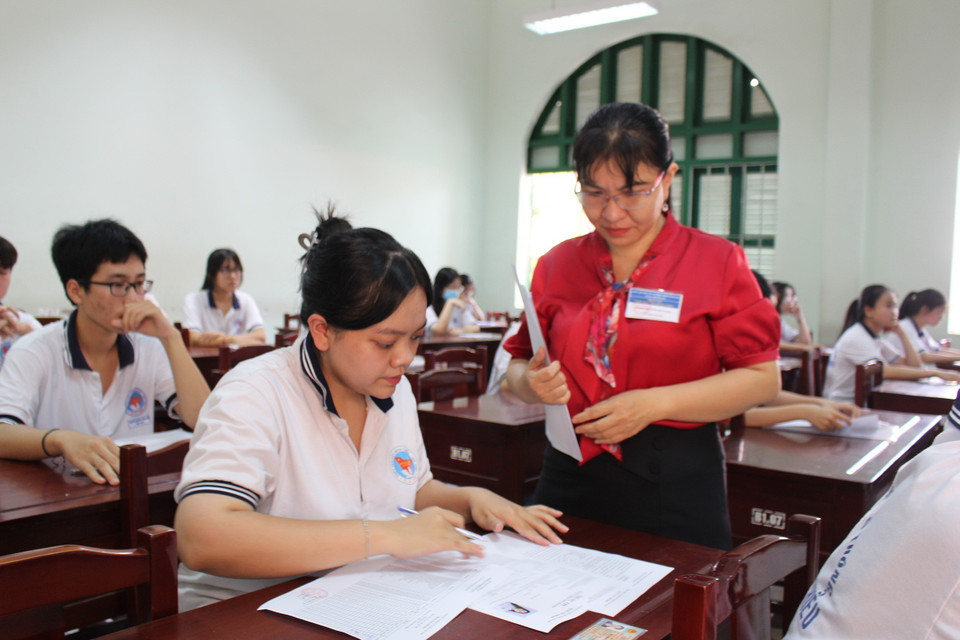 Thí sinh được cán bộ xem thi hướng dẫn điền thông tin đăng ký dự thi. (Ảnh: Hữu Chí/TTXVN)