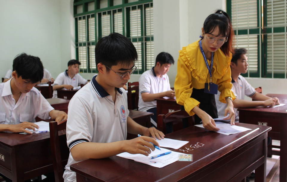 Cán bộ coi thi hướng dẫn thí sinh làm thủ tục đăng ký dự thi. (Ảnh: Hữu Chí/TTXVN)