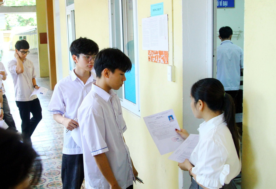Giám thị kiểm tra thẻ dự thi của các thí sinh trước khi vào phòng thi tại điểm thi Trường THPT Đào Duy Từ, thành phố Đồng Hới, tỉnh Quảng Bình. (Ảnh: Tá Chuyên/TTXVN)