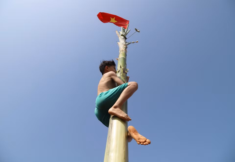 Vận động viên này đã cởi áo để tăng độ ma sát giữa cơ thể và thân chuối, quyết tâm leo lên cao hơn để giành phần thưởng. (Ảnh: Xuân Tiến/TTXVN)