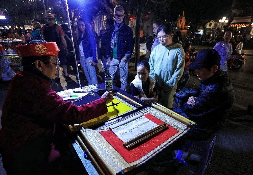 Một ông đồ già viết chữ cho những cô cậu học trò mong một năm học hành giỏi giang, đỗ đạt. (Ảnh: Tuấn Anh/TTXVN)