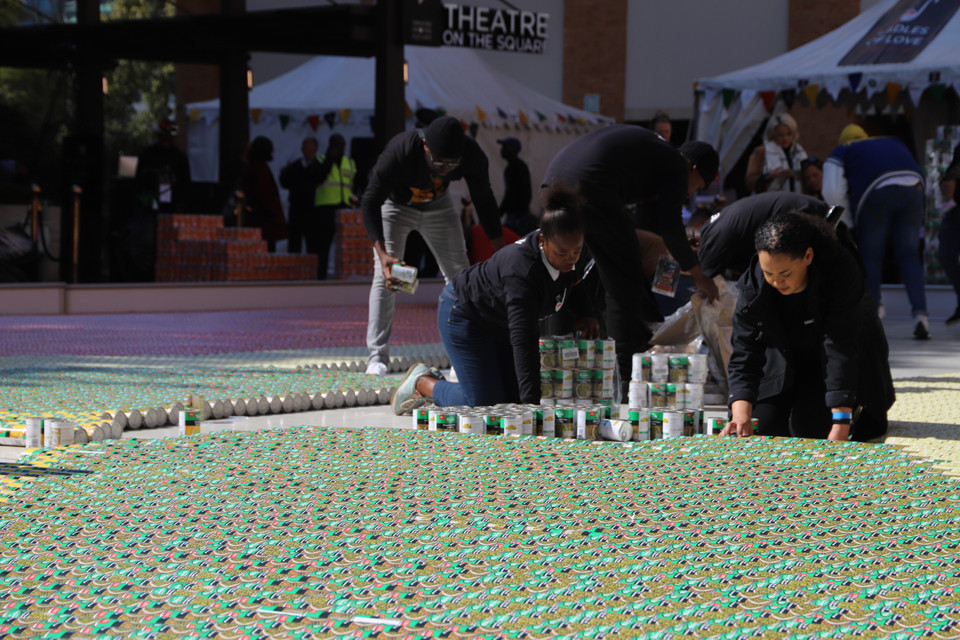 Các tình nguyện viên xếp bức tranh khảm lá Quốc kỳ Nam Phi bằng lon đồ hộp tại Quảng trường Nelson Mandela, thành phố Johannesburg. (Ảnh: Hồng Minh/TTXVN)