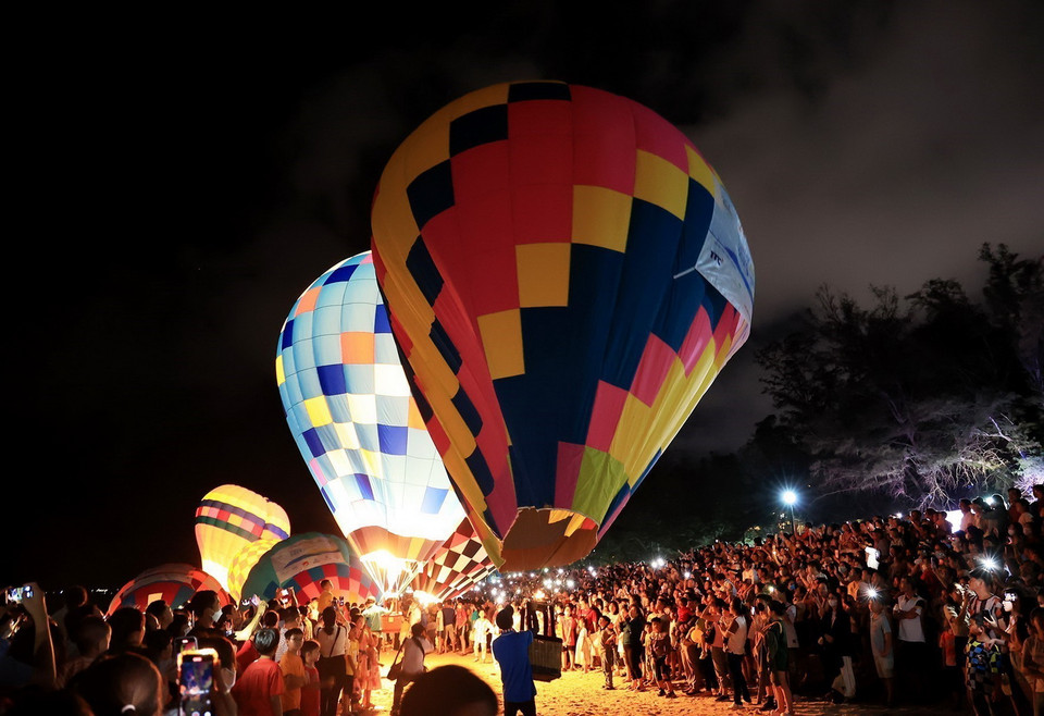 Du khách thưởng lãm khinh khí cầu nhiều màu sắc dưới bầu trời đêm biển Đồi Dương, thành phố Phan Thiết. (Ảnh: Hồng Đạt/TTXVN)