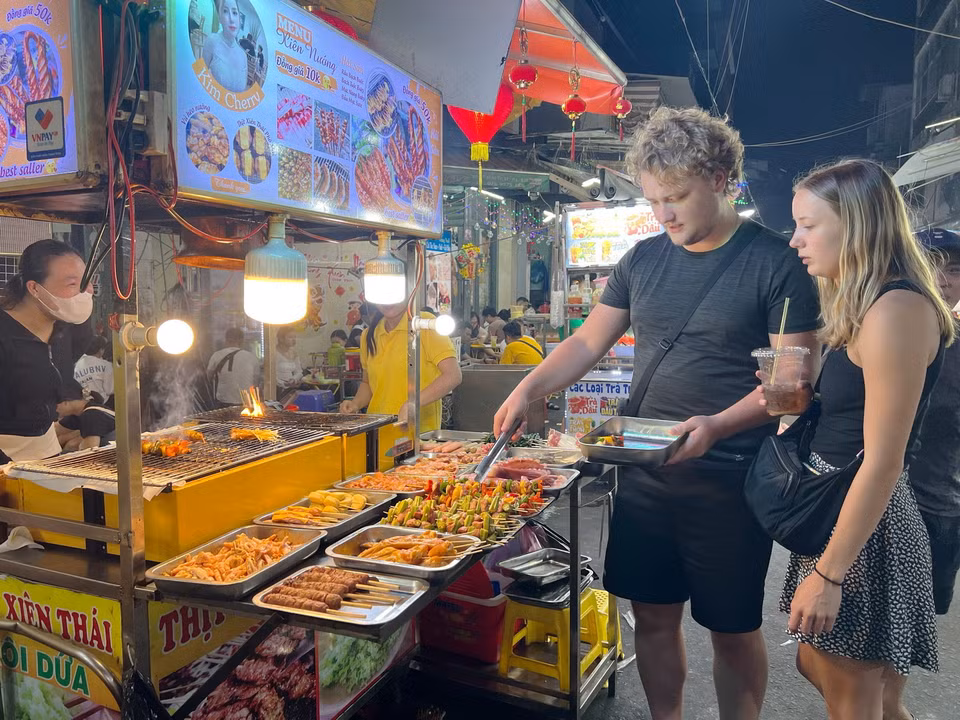 Những du khách nước ngoài trải nghiệm gian hàng tại phố ẩm thực Hồ Thị Kỷ, quận 10. (Ảnh: Thu Hương/TTXVN)