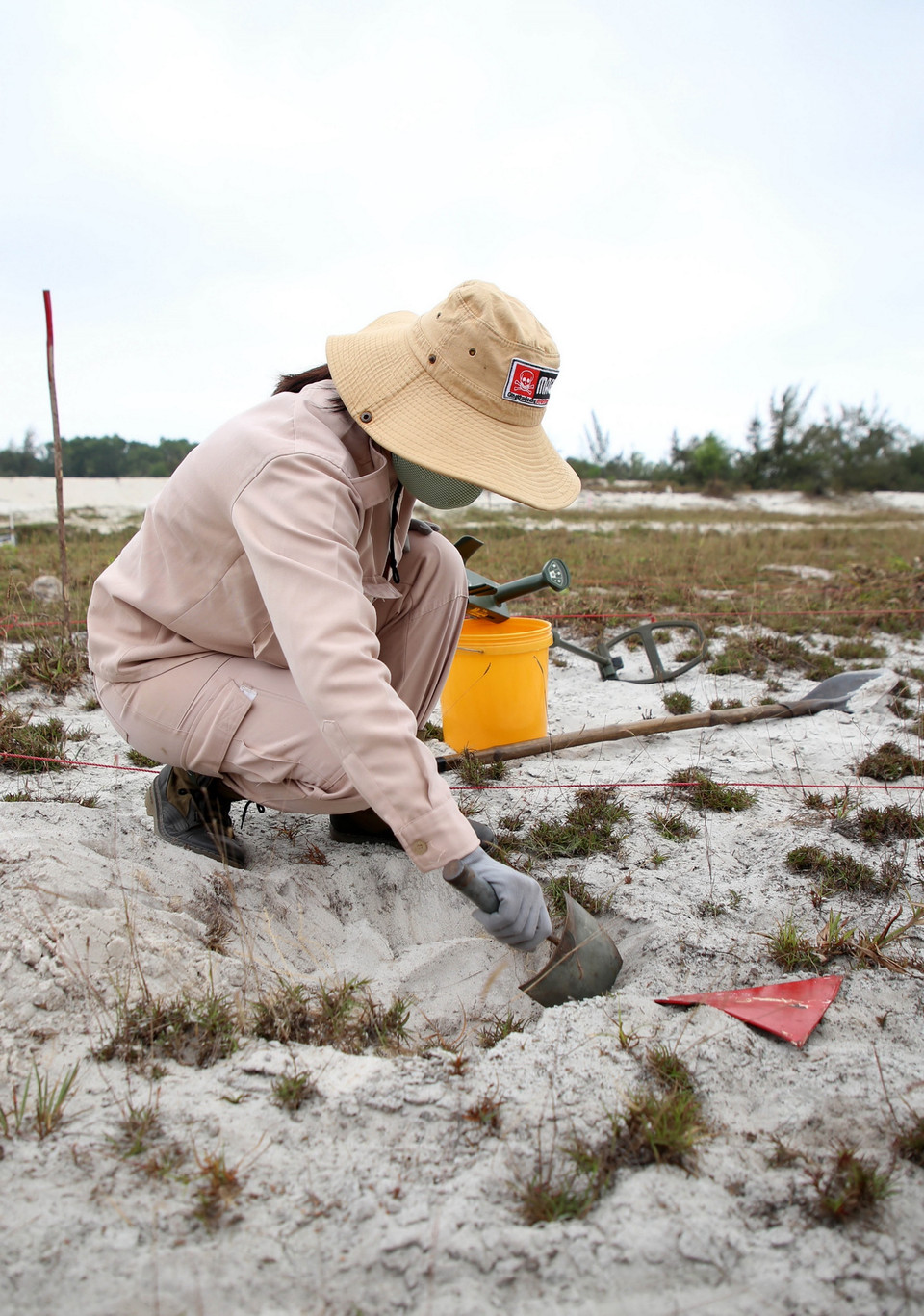 Những địa điểm máy rà phát ra tín hiệu bắt được kim loại, các thành viên đội MAT 19 sẽ đặt một tấm bìa màu đỏ để làm dấu. (Ảnh: Hồ Cầu/TTXVN)