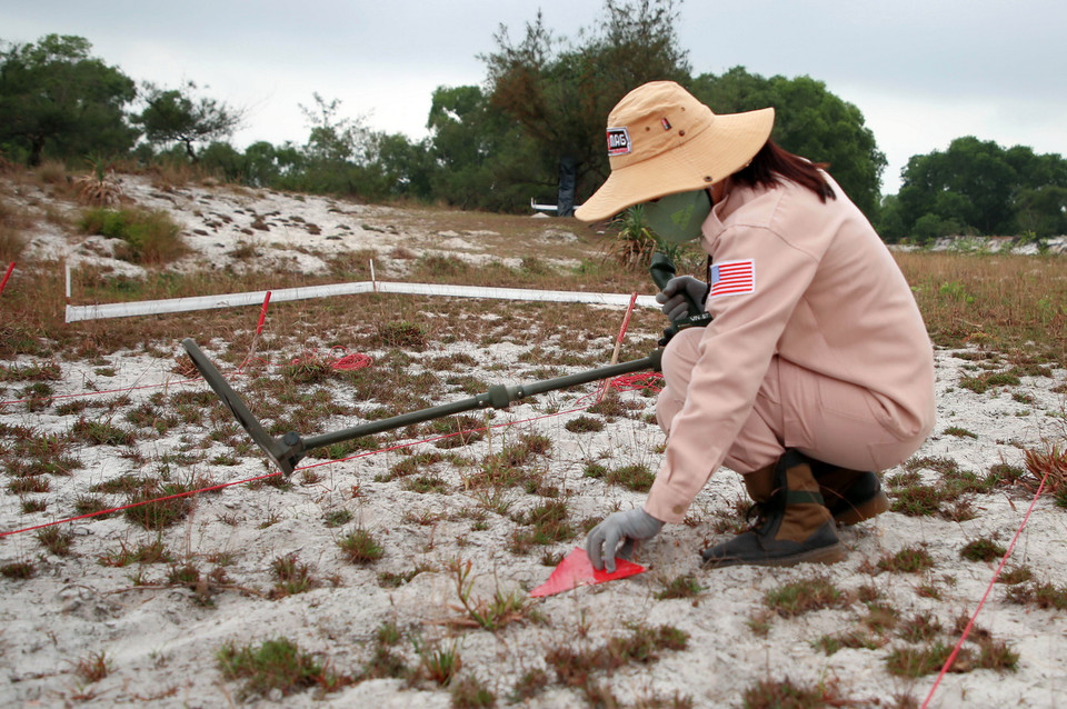 Các thành viên đội MAT 19 rà tìm các vật liệu nổ bằng máy chuyên dụng tại vùng cát huyện Hải Lăng. (Ảnh: Hồ Cầu/TTXVN)