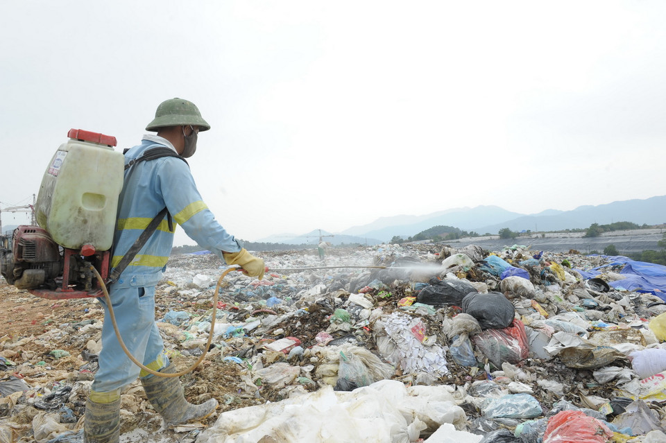 Công nhân Công ty TNHH MTV Môi trường Đô thị Hà Nội phun thuốc phòng trừ muỗi tại bãi rác Nam Sơn. (Ảnh: Mạnh Khánh/TTXVN)
