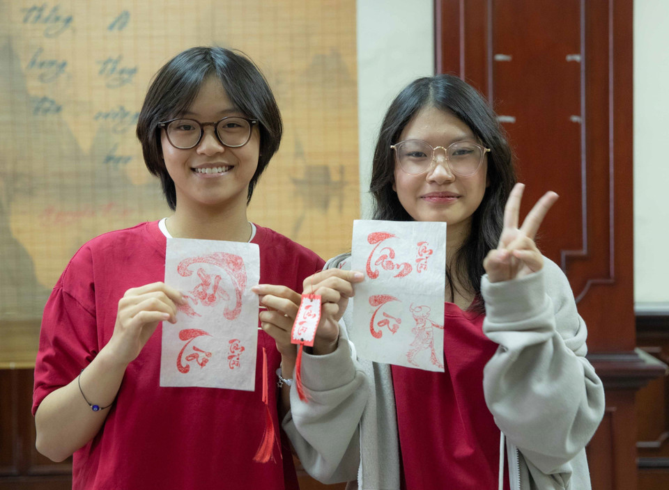 Du khách là những bạn trẻ thích thú với phần thưởng là tờ giấy có "chữ Tâm," "chữ Tài" do chính tay mình đóng lên sau khi giải thành công ô chữ tìm hiểu về những tác phẩm, nhà văn Việt Nam. (Ảnh: Hoàng Hiếu/TTXVN)