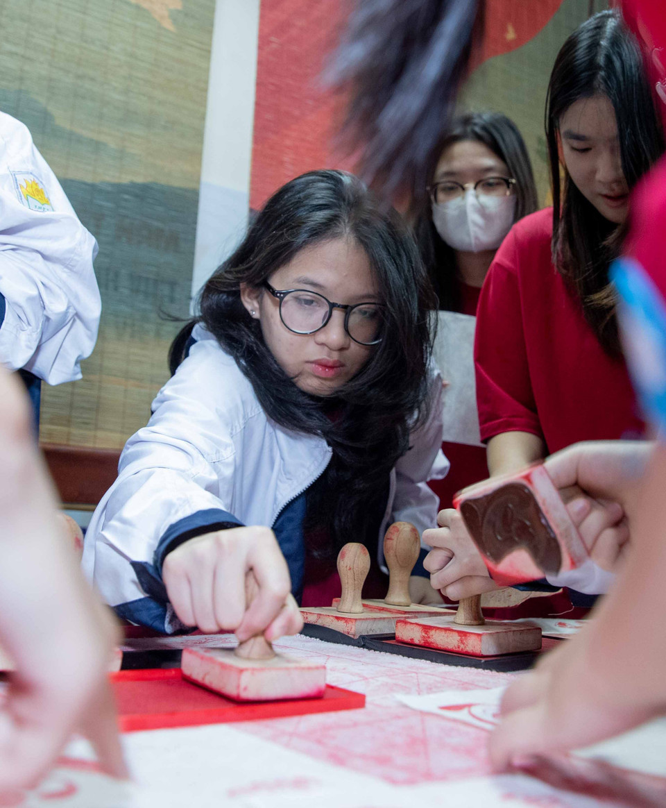 Các học sinh lấy dấu các chữ Tâm, chữ Tài làm kỷ niệm sau khi giải thành công ô chữ tìm hiểu về những tác phẩm, nhà văn Việt Nam. (Ảnh: Hoàng Hiếu/TTXVN)