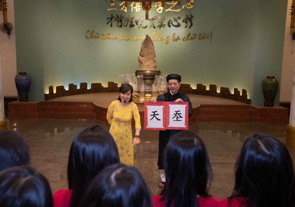 Nhân viên Bảo tàng Văn học Việt Nam giới thiệu khái quát cho du khách về nguồn gốc, quá trình phát triển của chữ Hán, chữ Nôm và chữ Quốc ngữ trong văn học Việt Nam. (Ảnh: Hoàng Hiếu/TTXVN)