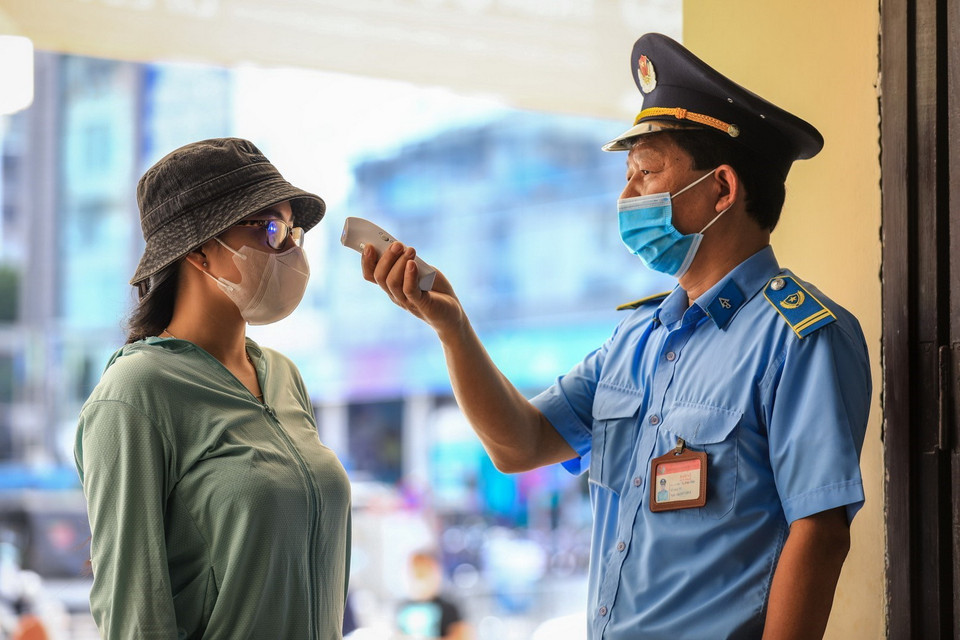  Nhân viên an ninh nhà ga Hà Nội kiểm tra thân nhiệt cho khách đến mua vé tàu sáng 12/10. (Ảnh: Thành Đạt/TTXVN)