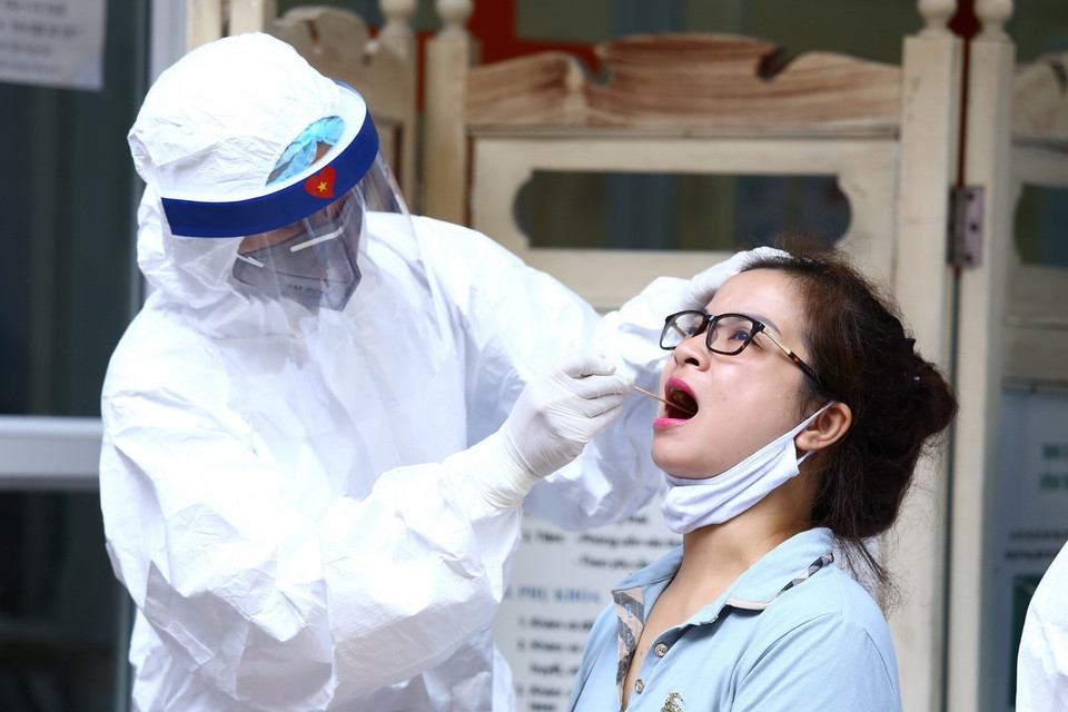 Nhân viên y tế lấy mẫu dịch hầu họng để xét nghiệm bằng phương pháp RT-PCR cho người dân trở về từ Đà Nẵng tại Nhà Hộ Sinh B - Trung Tâm Y Tế quận Hai Bà Trưng. (Ảnh: Minh Quyết/TTXVN)