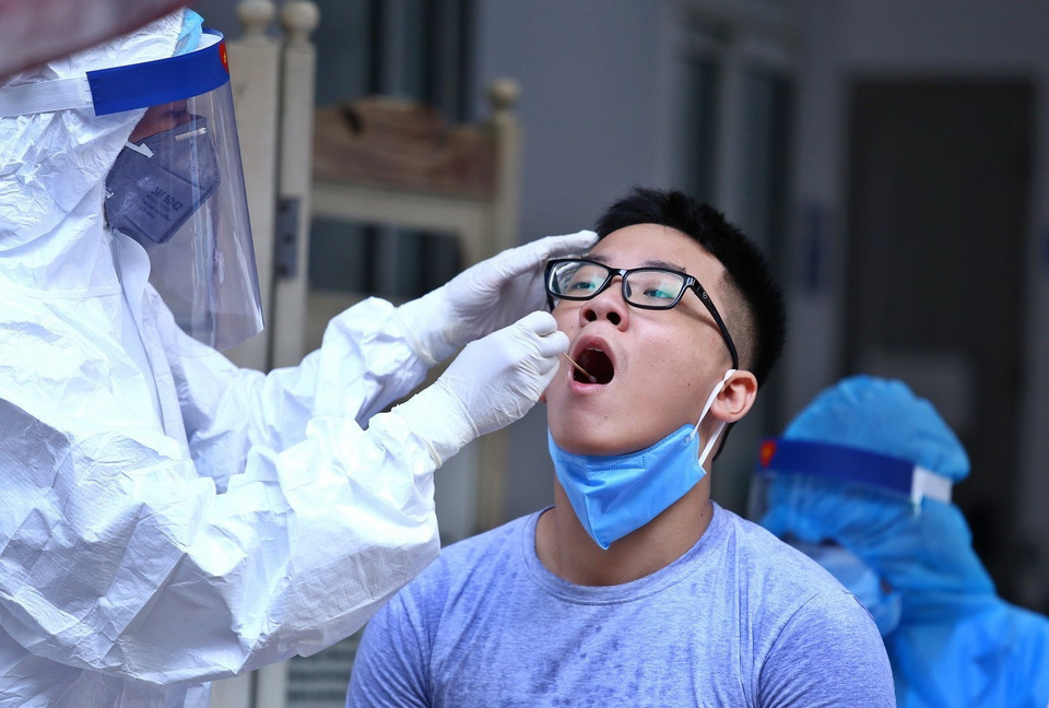 Nhân viên y tế lấy mẫu dịch hầu họng để xét nghiệm bằng phương pháp RT-PCR cho người dân trở về từ Đà Nẵng tại Nhà Hộ Sinh B - Trung Tâm Y Tế Quận Hai Bà Trưng. (Ảnh: Minh Quyết/TTXVN)