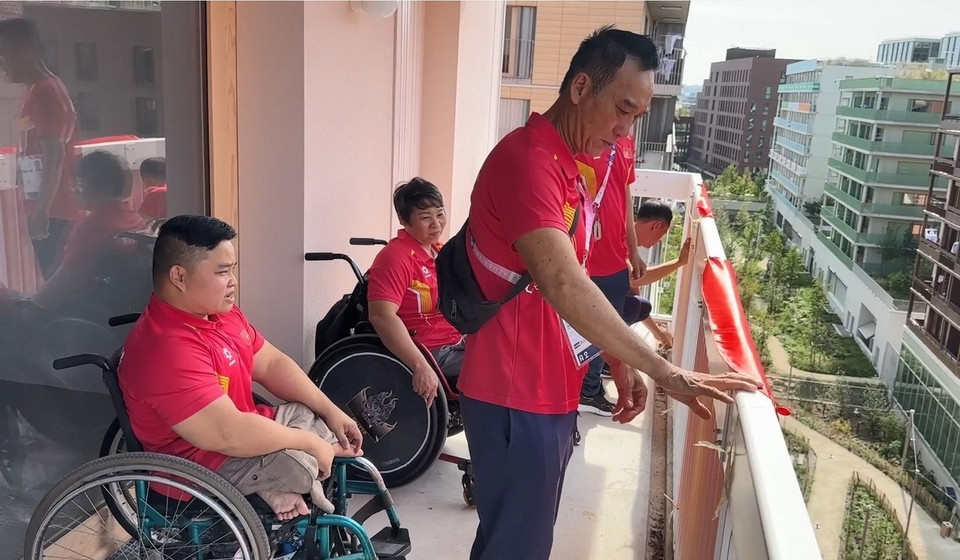 Các vận động viên Việt Nam đang treo cờ ngoài ban công nơi ở của đoàn Việt Nam. (Ảnh: Ngọc Hiệp/TTXVN)