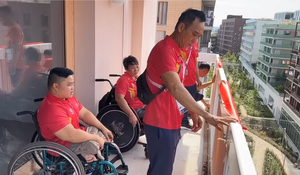 Các vận động viên Việt Nam đang treo cờ ngoài ban công nơi ở của đoàn Việt Nam. (Ảnh: Ngọc Hiệp/TTXVN)