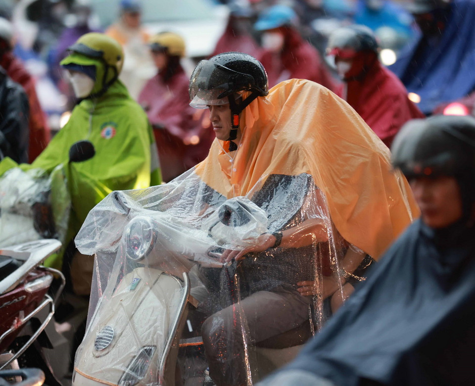 Người dân di chuyển khó khăn trong mưa vào đầu giờ sáng 23/7. (Ảnh: Thanh Tùng/TTXVN)