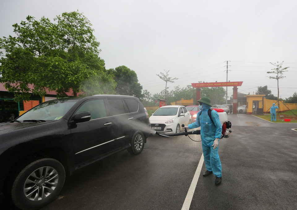 Phun hóa chất khử khuẩn phương tiện vào đón công dân hoàn thành thời gian cách ly tại Trung đoàn 58. (Ảnh: Dương Giang/TTXVN)