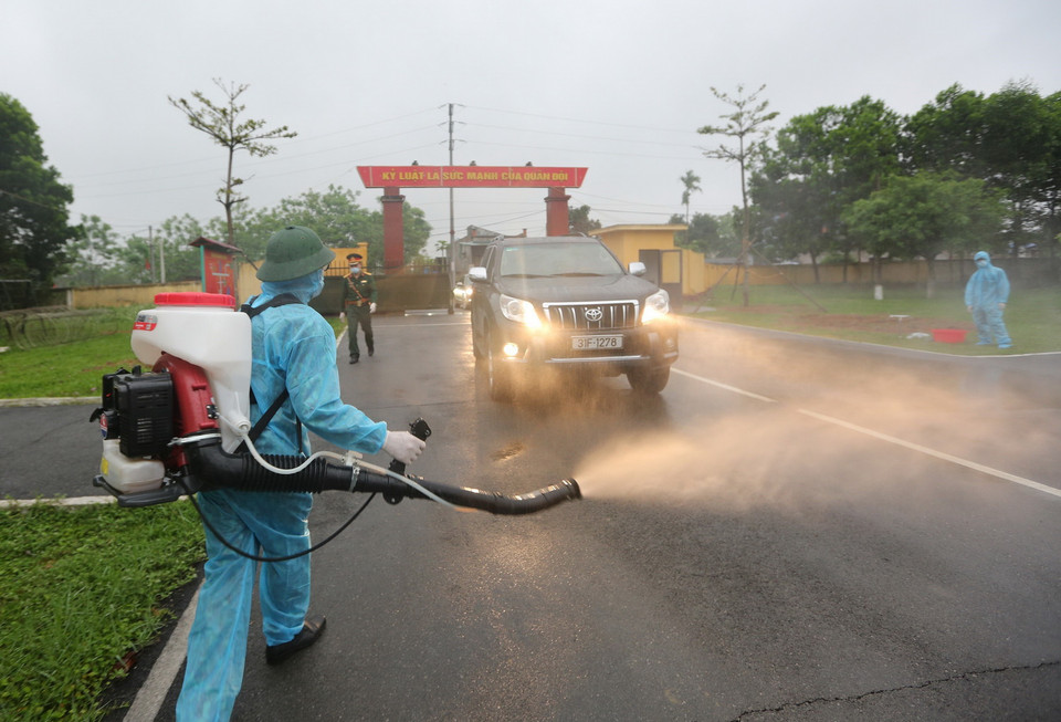 Phun hóa chất khử khuẩn phương tiện vào đón công dân hoàn thành thời gian cách ly tại Trung đoàn 58. (Ảnh: Dương Giang/TTXVN)