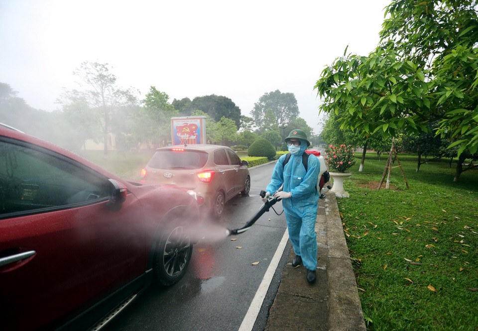 Phun hóa chất khử khuẩn phương tiện vào đón công dân hoàn thành thời gian cách ly tại Trung đoàn 58. (Ảnh: Dương Giang/TTXVN)