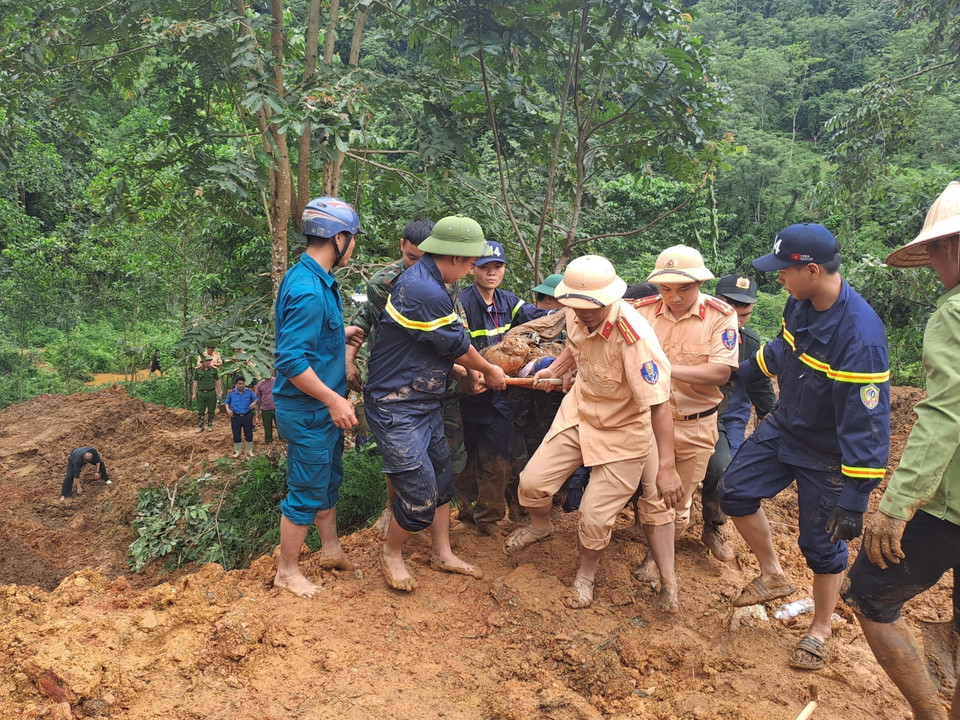 Các lực lượng tìm kiếm đưa thi thể nạn nhân bị vùi lấp ra khỏi khu vực sạt lở. (Ảnh: Đức Thọ/TTXVN)