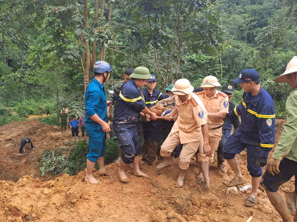 Các lực lượng tìm kiếm đưa thi thể nạn nhân bị vùi lấp ra khỏi khu vực sạt lở. (Ảnh: Đức Thọ/TTXVN)