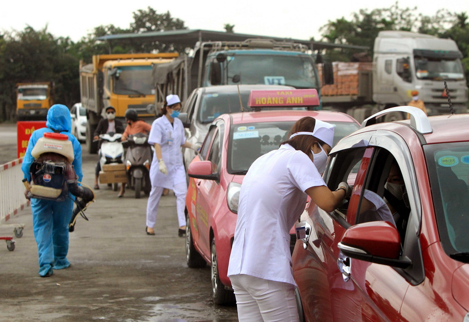 Nhân viện y tế kiểm tra thân nhiệt cho người tham gia giao thông tại chốt huyện Thủy Nguyên trước khi vào thành phố. (Ảnh: An Đăng/TTXVN)