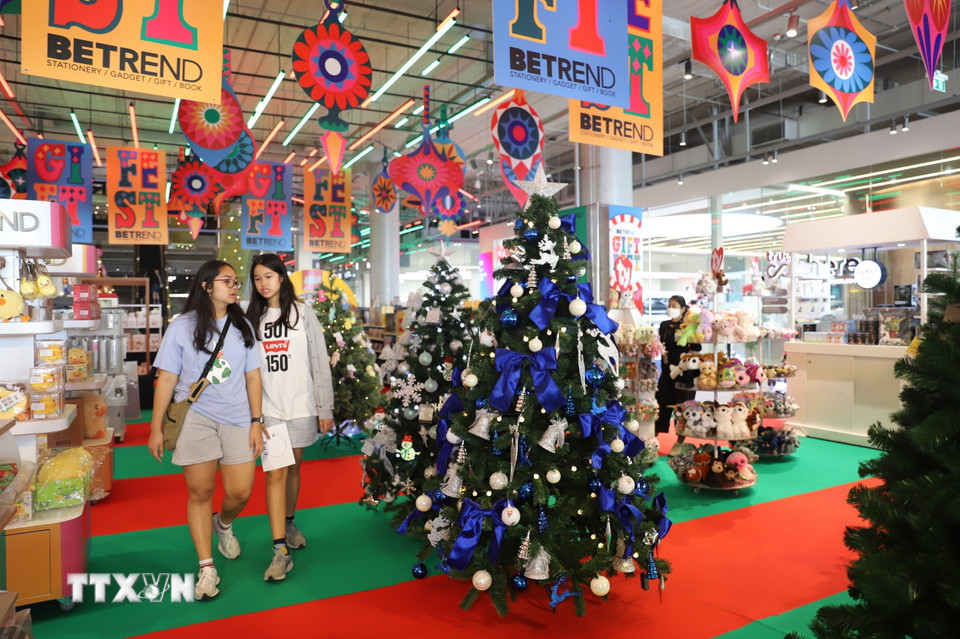 Hai bạn trẻ đi qua những cây thông Noel được trang trí bắt mắt bên trong Chợ Giáng sinh ở Trung tâm Thương mại Emsphere. (Ảnh: Đỗ Sinh/TTXVN)