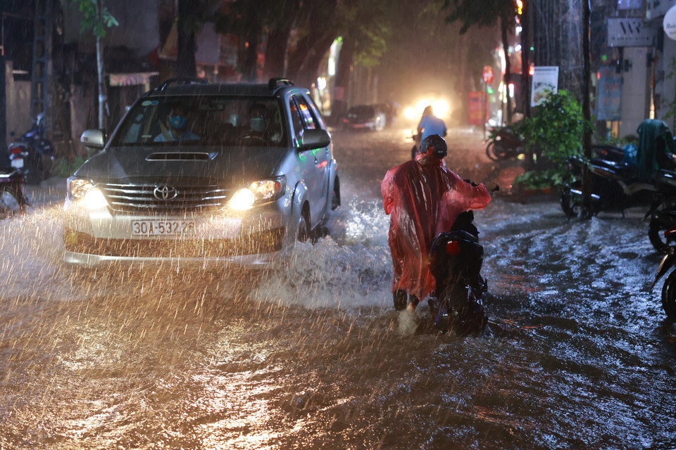 Các phương tiện di chuyển qua các tuyến phố ngập sâu rất khó khăn. (Ảnh: Minh Sơn/Vietnam+)