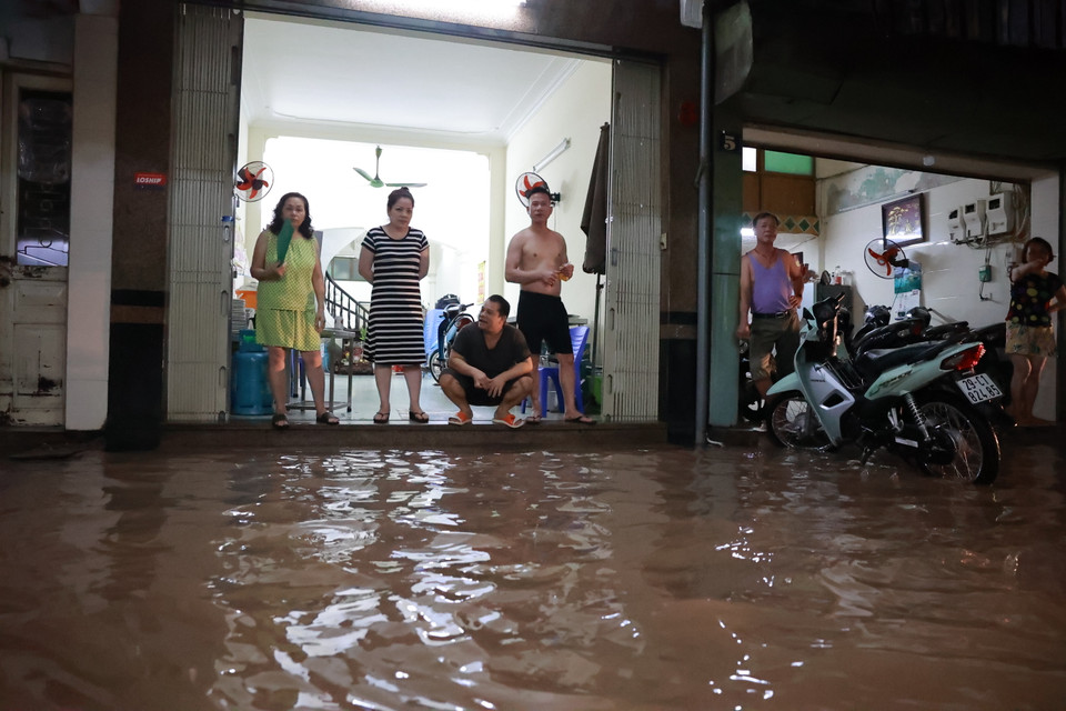 Nhiều người dân chuẩn bị sẵn sàng tinh thần tát nước ra khỏi nhà. (Ảnh: Minh Sơn/Vietnam+)