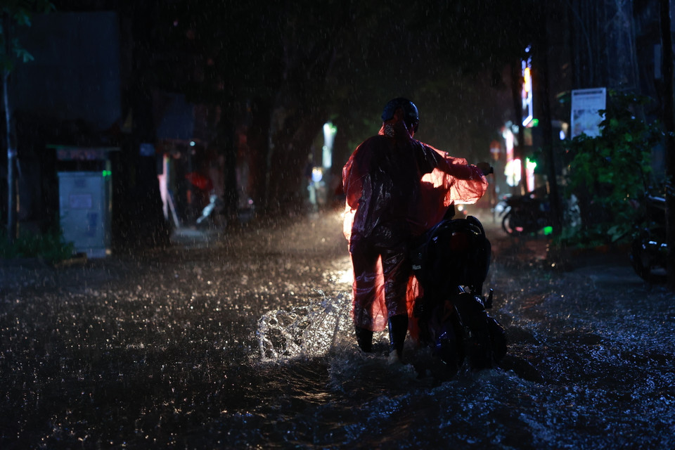 Các phương tiện di chuyển qua các tuyến phố ngập sâu rất khó khăn. (Ảnh: Minh Sơn/Vietnam+)
