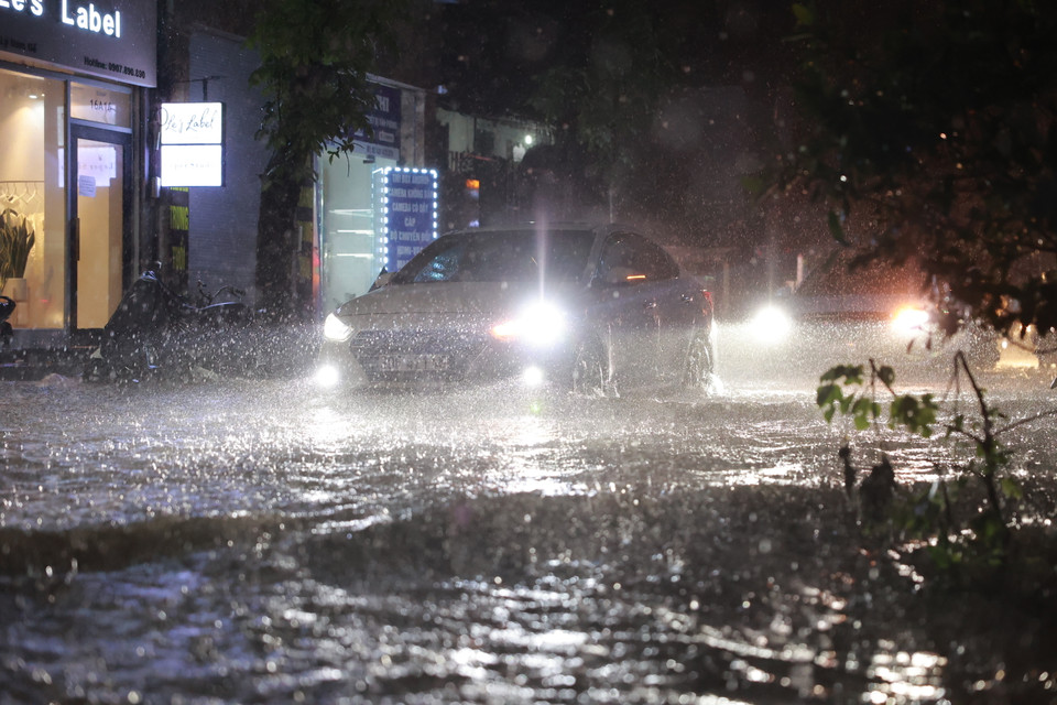 Các phương tiện di chuyển qua phố Lý Nam Đế rất khó khăn vì lượng nước dâng cao không kịp thoát. (Ảnh: Minh Sơn/Vietnam+)