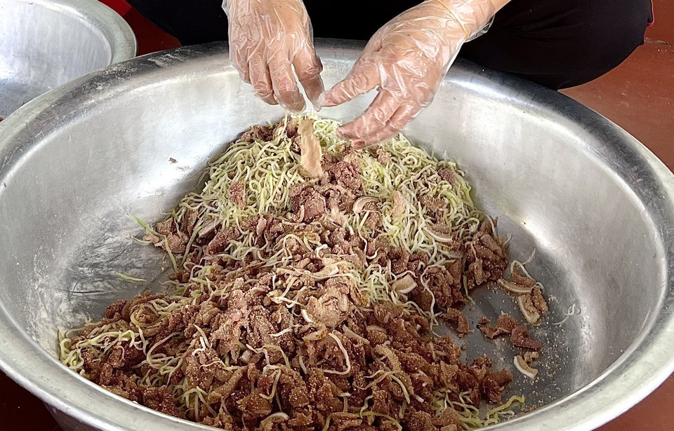 Đu đủ xanh, cạo sạch vỏ, rửa sạch, bào thành sợi, cho vào khuôn ép hết nước rồi trộn cùng thịt lợn và thính gạo rồi mang đi nén chặt trong lọ để trong 3-5 ngày là có thể mang ra ăn được. (Ảnh: Tạ Toàn/TTXVN) 