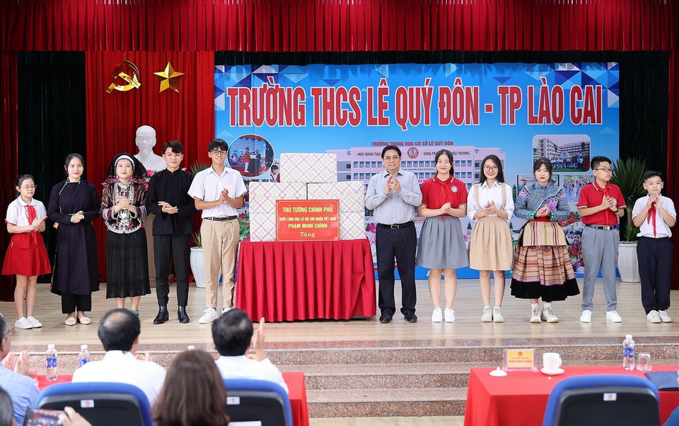 Thủ tướng Phạm Minh Chính tặng quà cho giáo viên, học sinh cụm liên trường học thành phố Lào Cai. (Ảnh: Dương Giang/TTXVN)