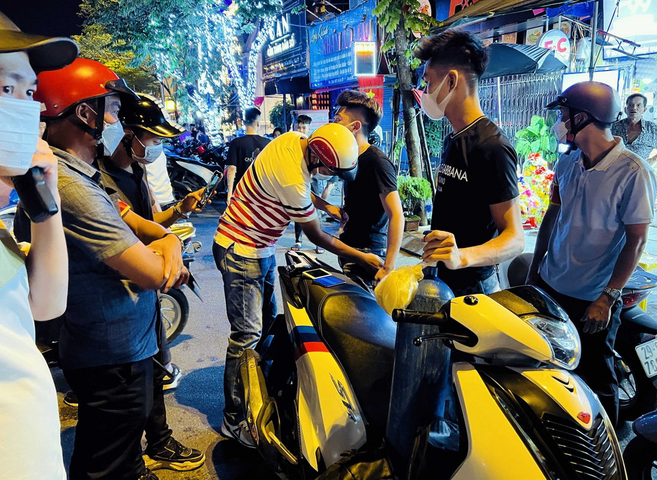 Tại đường Trần Nhật Duật (đoạn lối lên cầu Long Biên), tổ công tác Y1/141 đã phát và xử lý hai thanh niên không đội mũ bảo hiểm, chở theo bình bóng cười kèm nhiều vỏ bóng. (Ảnh: Phạm Kiên/TTXVN)