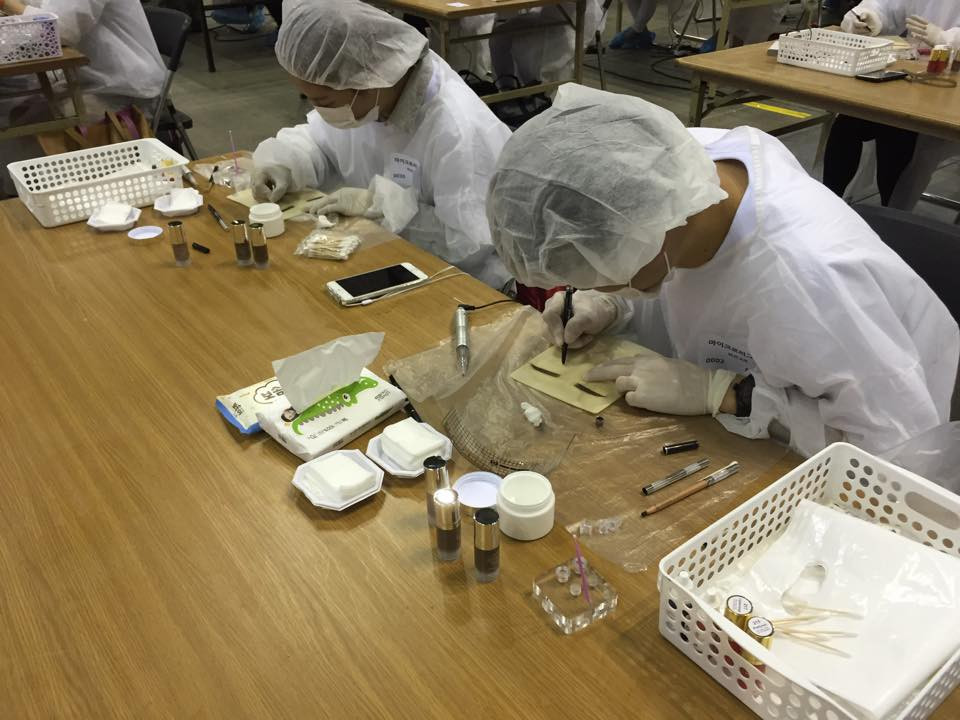 Các kỹ thuật đang thực hiện phần thi xăm lông mày. (Ảnh: Khánh Ly/Vietnam+)