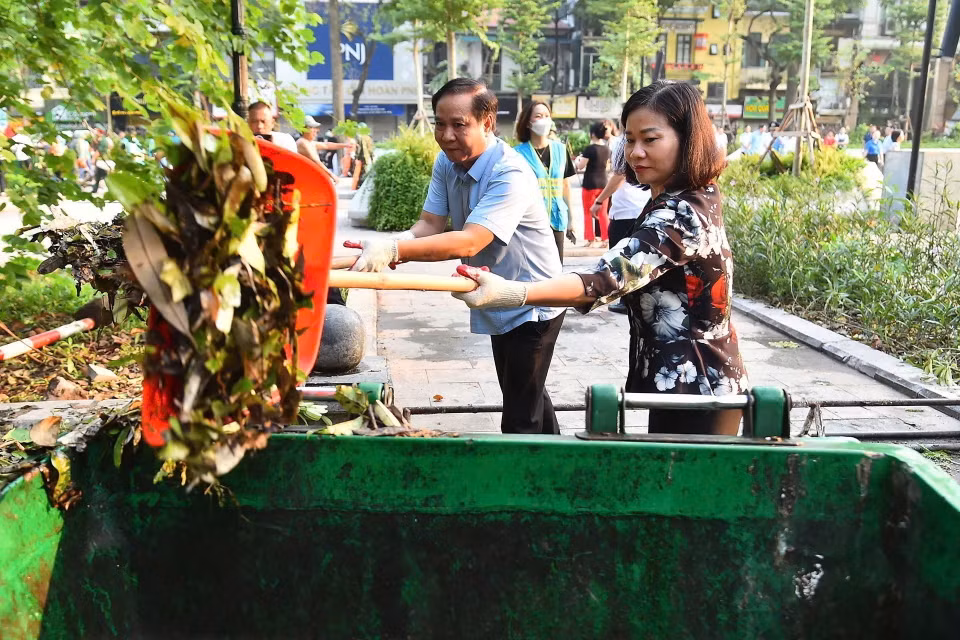 Phó Bí thư Thường trực Thành ủy Nguyễn Thị Tuyến tham gia vệ sinh môi trường cùng người dân tại Vườn hoa Vạn Xuân. (Ảnh: TTXVN phát)