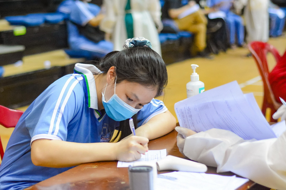  Học sinh viết phiếu cam kết tiêm chủng. (Ảnh: Văn Dũng/TTXVN)