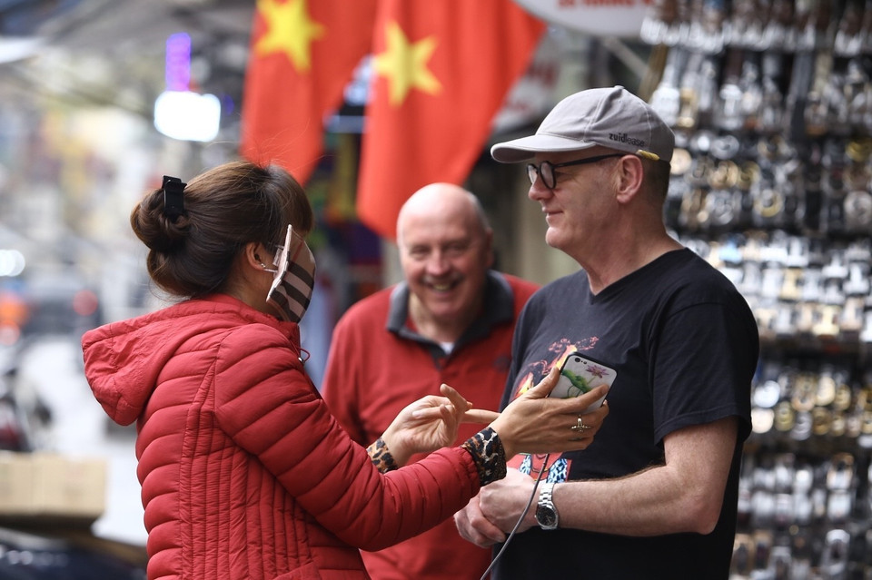 Du khách mua hàng hoá trên phố Hàng Ngang cũng không quan tâm đeo khẩu trang. (Ảnh: Minh Quyết/TTXVN)