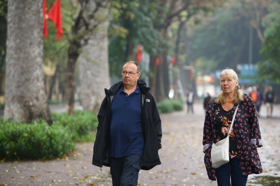 Nhiều du khách thản nhiên đi dạo quanh hồ Hoàn Kiếm mà không đeo khẩu trang. (Ảnh: Minh Quyết/TTXVN)