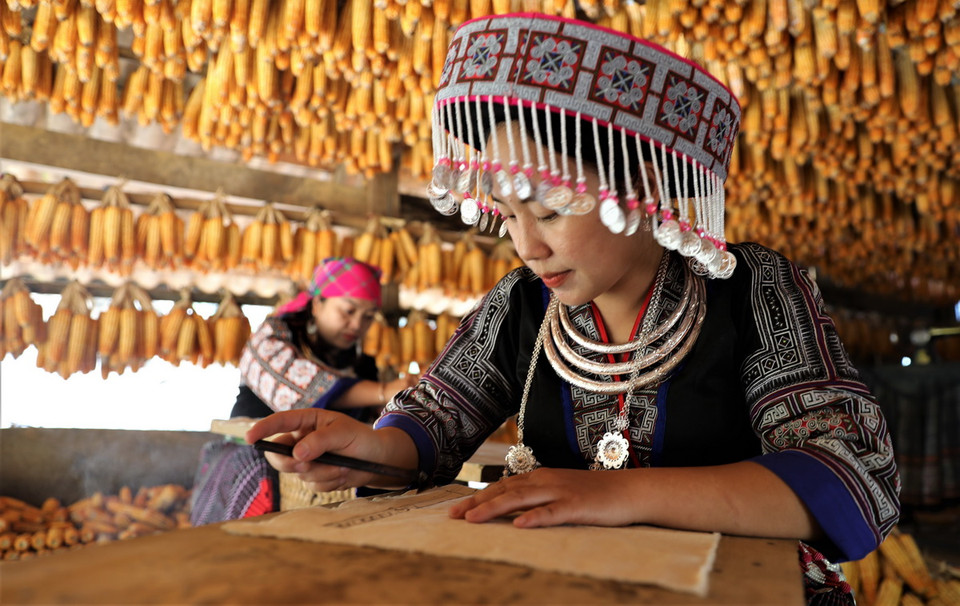 Du khách trải nghiệm vẽ tranh bằng sáp ong tại Nhà ngô Màng Mủ. (Ảnh: Tuấn Anh/TTXVN)