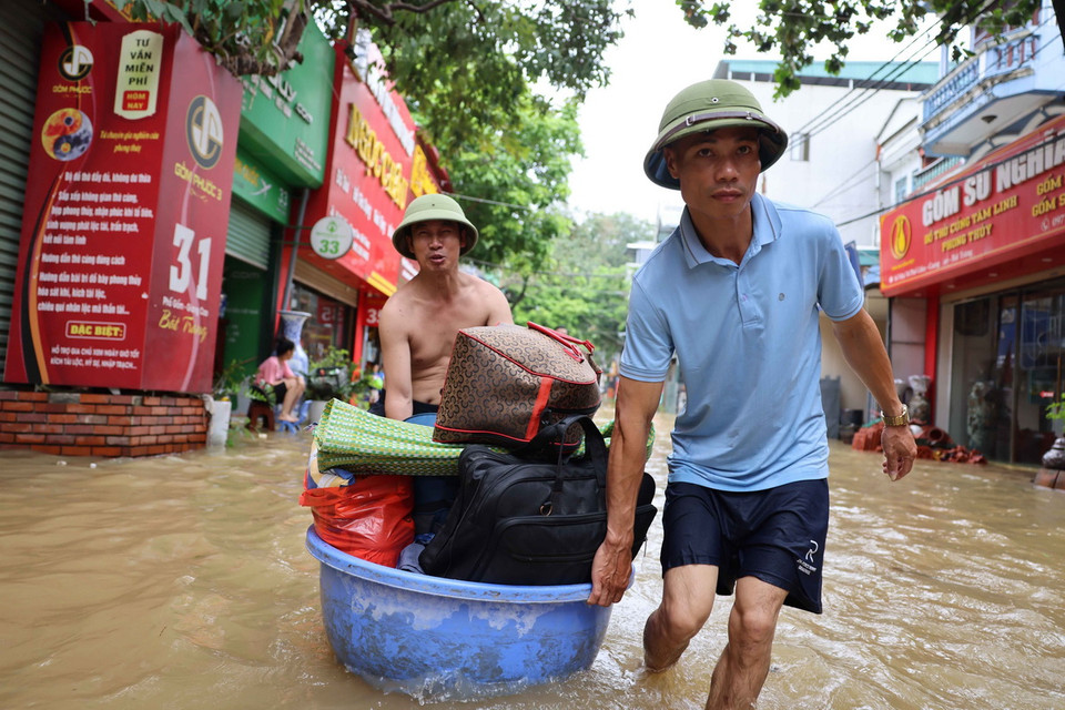 Người dân di chuyển đồ đạc ra khỏi vùng lụt ở xã Bát Tràng. (Ảnh: Thanh Tùng/TTXVN)
