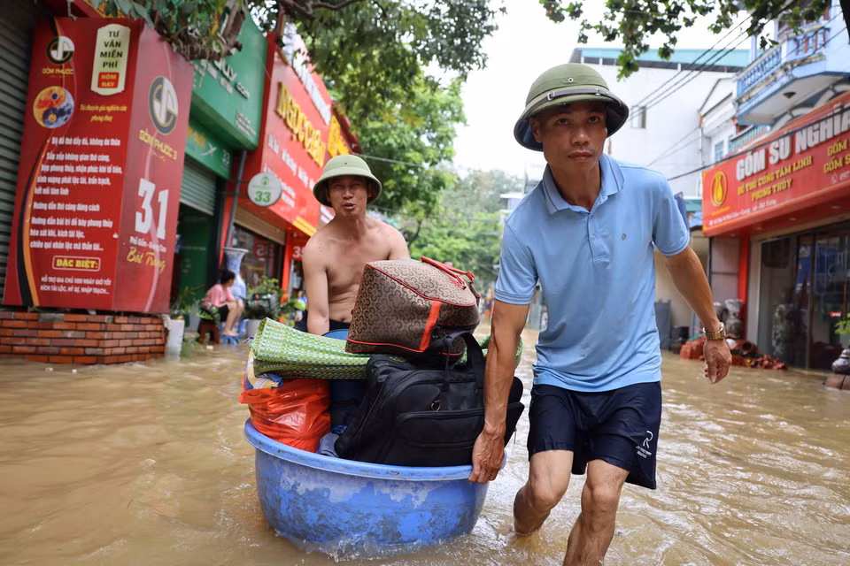 Người dân di chuyển đồ đạc ra khỏi vùng lụt ở xã Bát Tràng. (Ảnh: Thanh Tùng/TTXVN)