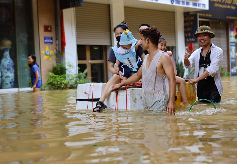 Người dân xã Bát Tràng dùng nhiều vật dụng khác nhau để có thể di chuyển như thuyền, bè trên đường bị ngập. (Ảnh: Thanh Tùng/TTXVN)