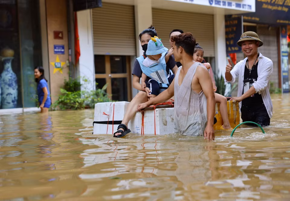 Người dân xã Bát Tràng dùng nhiều vật dụng khác nhau để có thể di chuyển như thuyền, bè trên đường bị ngập. (Ảnh: Thanh Tùng/TTXVN)