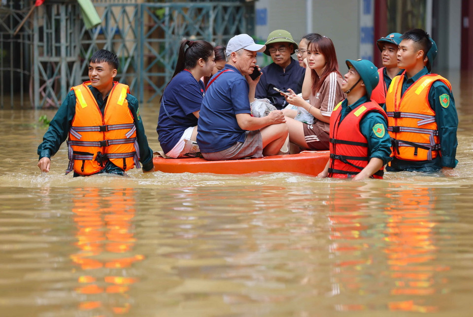 Lực lượng quân đội, dân quân xã giúp người dân di chuyển ra khỏi vùng ngập. (Ảnh: Thanh Tùng/TTXVN)