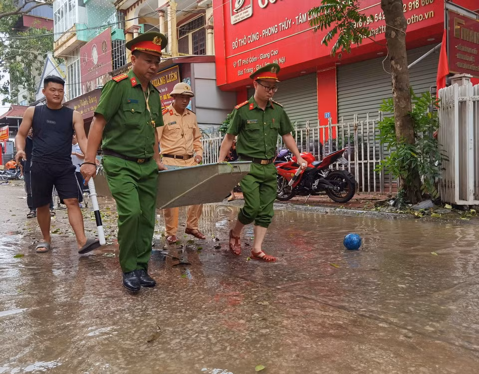 Lực lượng công an hỗ trợ chuyển thuyền nhỏ để giúp người dân di chuyển trong vùng lụt. (Ảnh: Thanh Tùng/TTXVN)