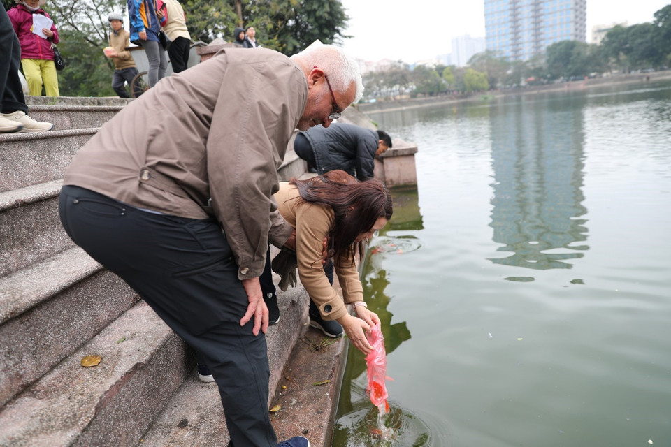 Người nước ngoài háo hức với phong tục thả cá chép để tiễn đưa ông Táo về trời. (Ảnh: Thành Đạt/TTXVN)