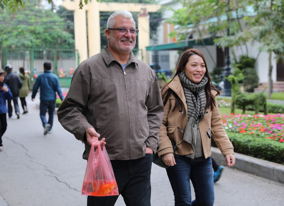 Người nước ngoài háo hức với phong tục thả cá chép để tiễn đưa ông Táo về trời. (Ảnh: Thành Đạt/TTXVN)