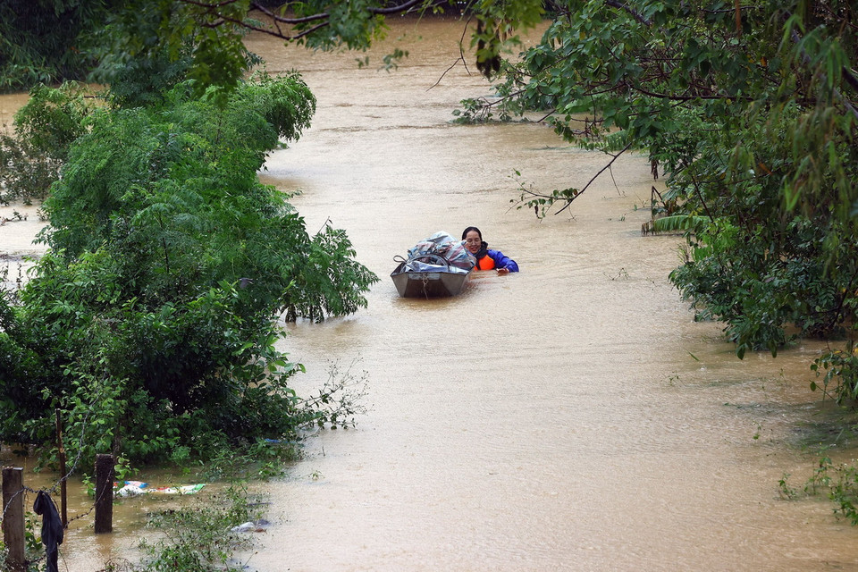 Một người dân xã Thọ Xuân (huyện Đan Phượng) đang cố gắng đưa tài sản vào khu vực đê sông Hồng (ảnh chụp lúc 12h15). (Ảnh: Huy Hùng/TTXVN)