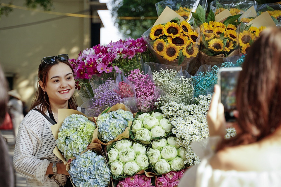 Các bạn trẻ chụp ảnh chung với xe hoa rực rỡ sắc màu. (Ảnh: Khánh Hoà/TTXVN)